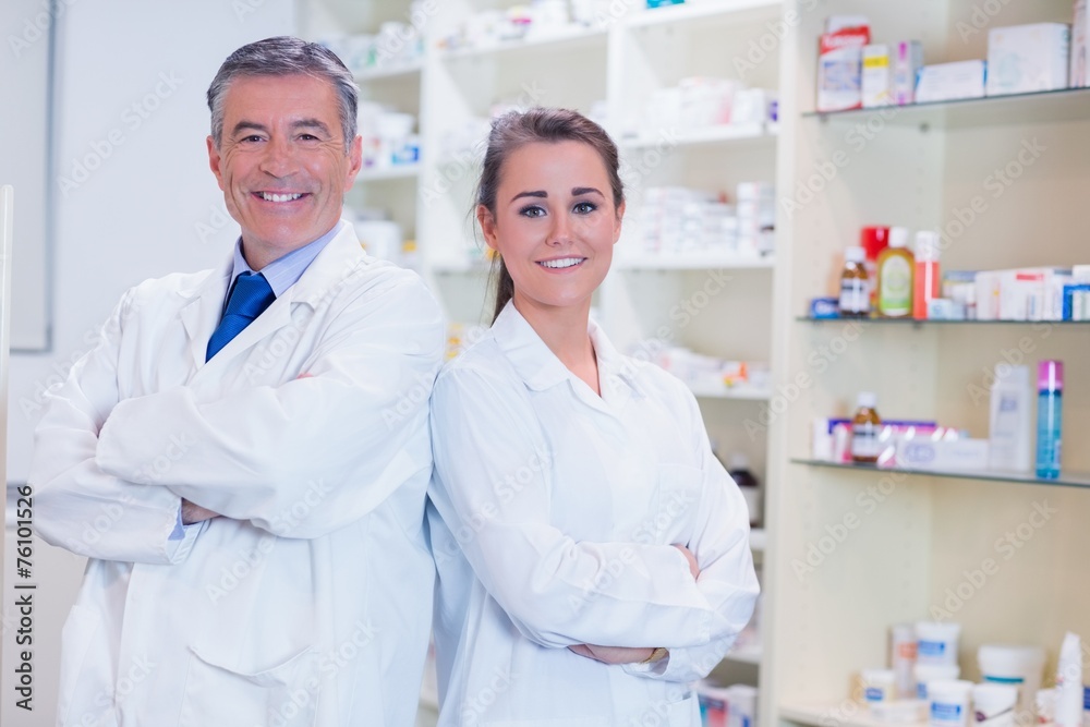 Pharmacist with his trainee standing with arms crossed Pharmacist with his trainee standing with arms crossed