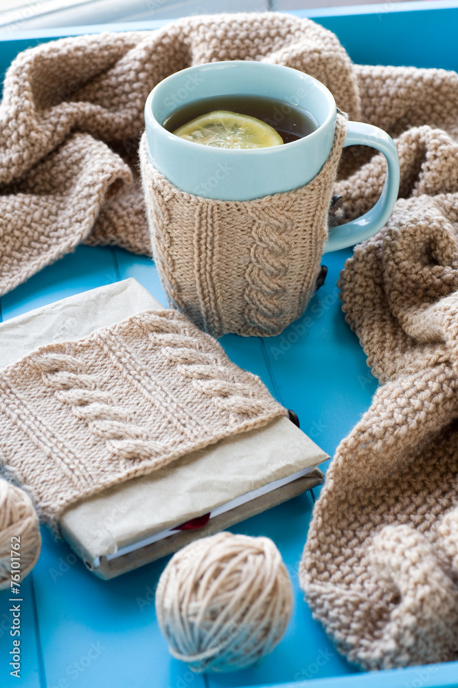 A cup of tea with lemon in sweater, old notebook, beige knitted A cup of tea with lemon in sweater, old notebook, beige knitted