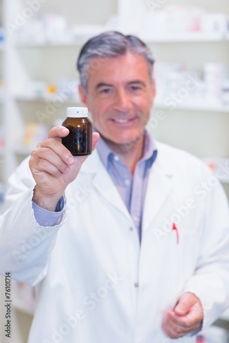 Pharmacist showing a drug bottle to camera