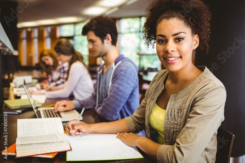 Student looking at camera while studying with classmates