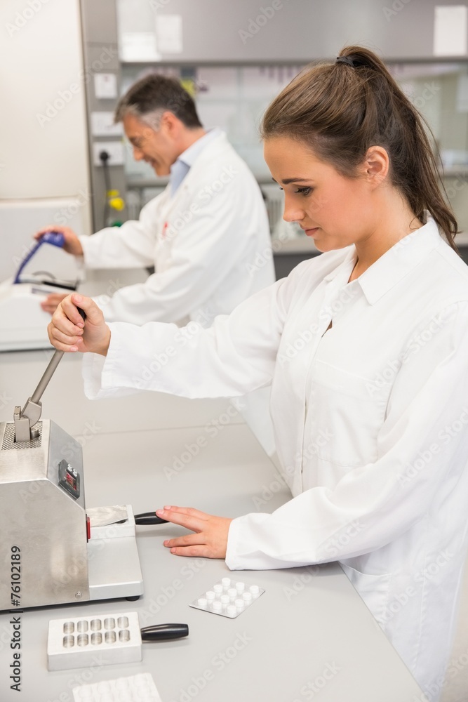 Pharmacist using press to make pills Pharmacist using press to make pills