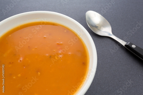 Tomato bisque soup with shrimp and spoon on a dark background