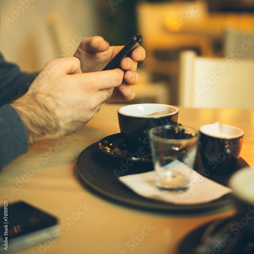 man in coffee shop using smart phone