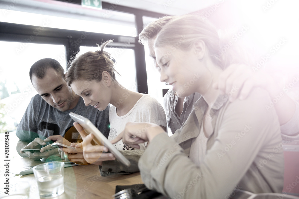 Obraz premium Group of friends in campus lounge websurfing with tablet