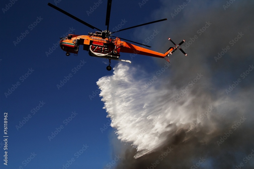 Firefigthers are fighting with bushfire. Helicopter drops water from the sea Firefigthers are fighting with bushfire. Helicopter drops water from the sea