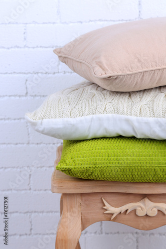 Pillows on small wooden table and white brick wall background