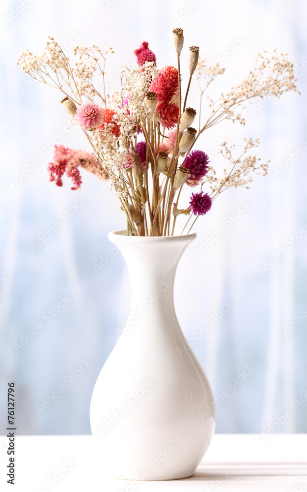 Bouquet of dried flowers in vase on light background