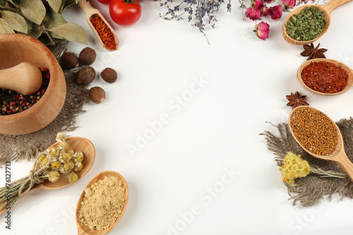 Different spices and herbs in wooden spoons isolated on white