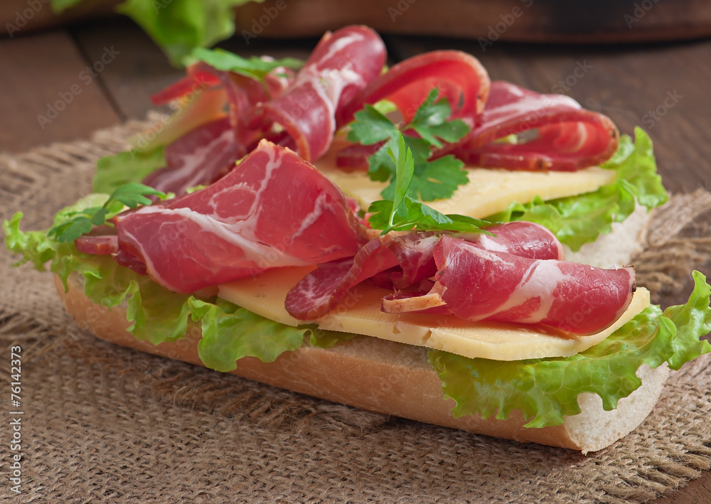 Big sandwich with raw smoked meat on a wooden background