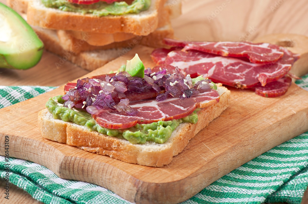 Sandwich with ham, avocado sauce and caramelized onions