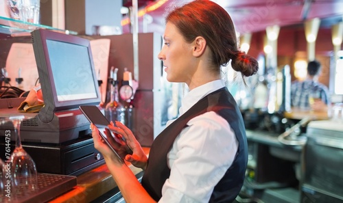Billede på lærred Focused barmaid using touchscreen till