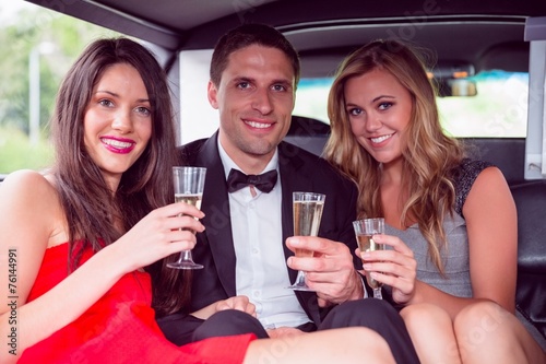 Happy friends drinking champagne in limousine