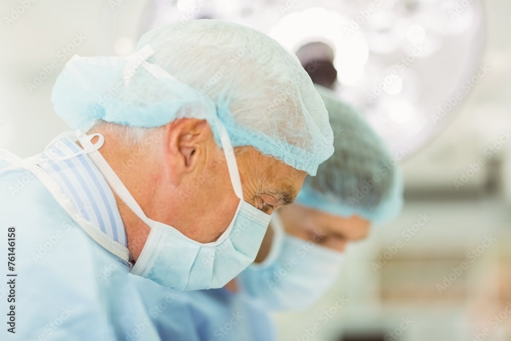 Naklejka premium Older surgeon teaching new surgeon how to operate