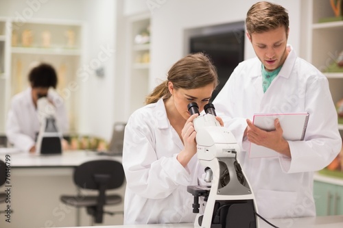Happy medical students working with microscope