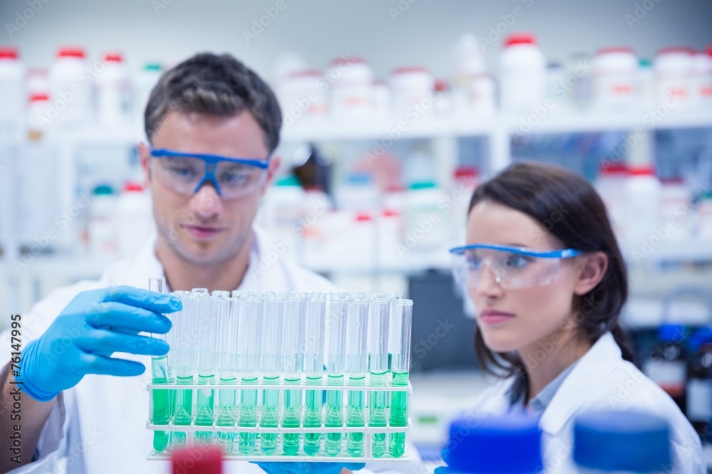 Chemist holding test tube tray with his colleague next to him Chemist holding test tube tray with his colleague next to him