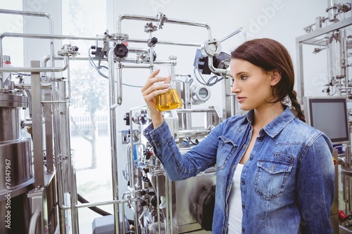 Stylish brunette in denim jacket looking at beaker of beer