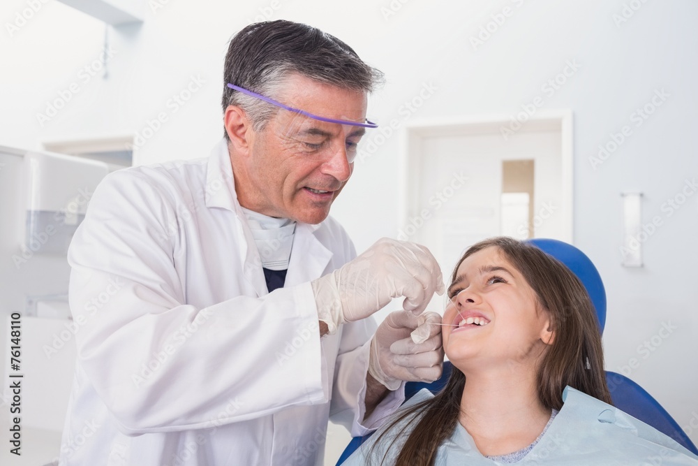 Pediatric dentist using dental floss to his young patient Pediatric dentist using dental floss to his young patient