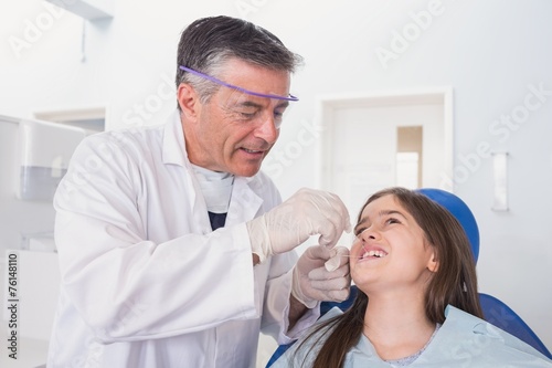 Pediatric dentist using dental floss to his young patient