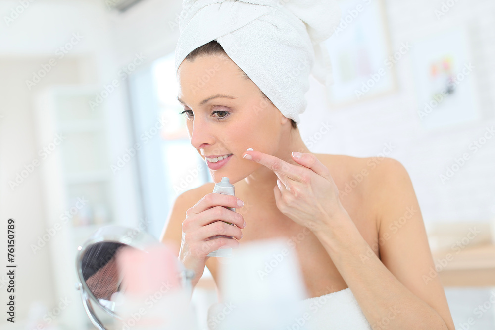 Beautiful woman applying moisturizing cream on her face Beautiful woman applying moisturizing cream on her face