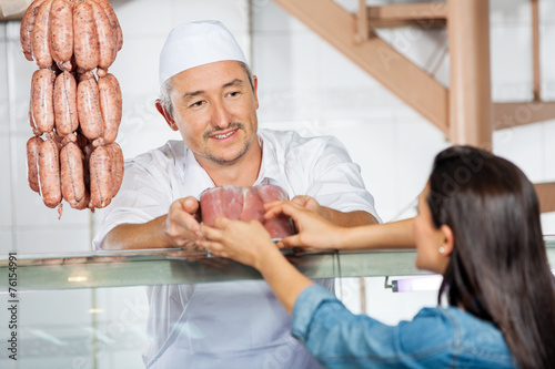 Butcher Giving Pack Of Sausages To Customer