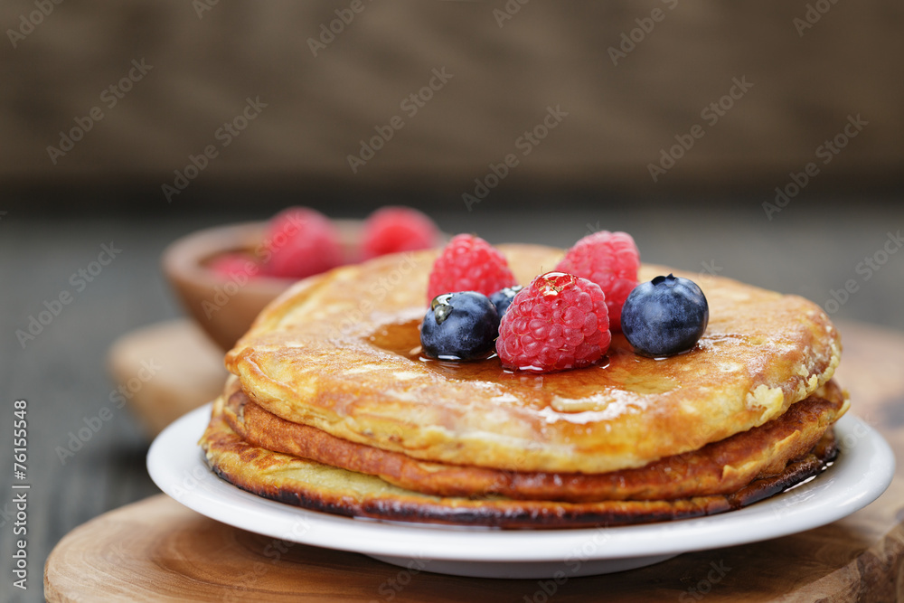 Pancakes with berries and maple syrup, on wooden table Pancakes with berries and maple syrup, on wooden table