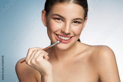 Seductive young woman with lip brush