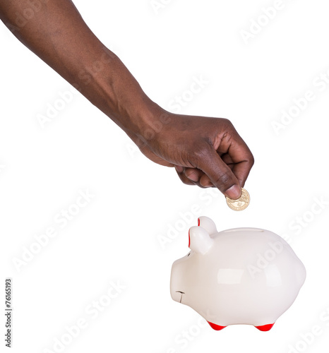 Male hand putting a coin into a piggy bank