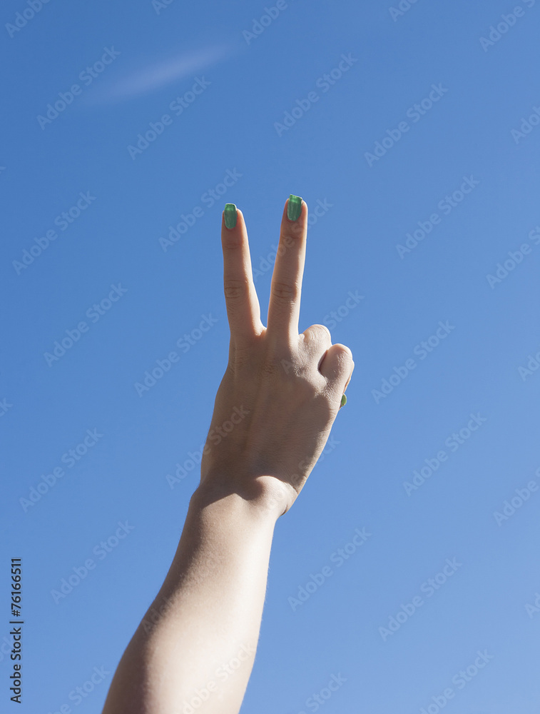 Female hand up in the sky making victory gesture Female hand up in the sky making victory gesture