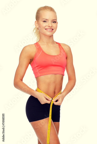 smiling sporty woman with measuring tape © Syda Productions