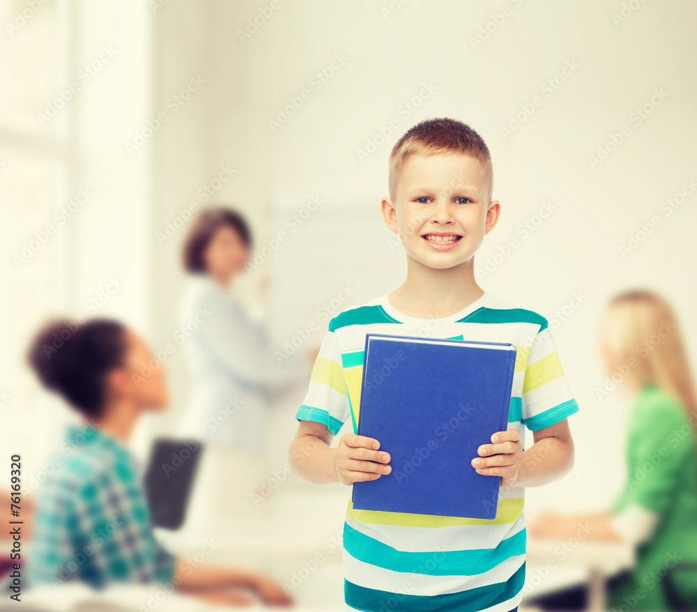 smiling little student boy with blue book