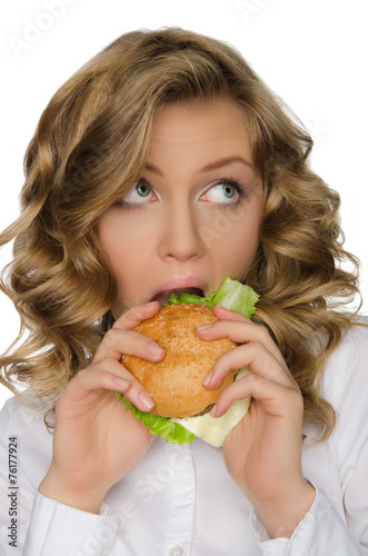 Young woman biting burger and looking away