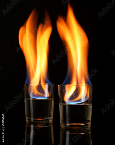 Glasses with burning alcohol on black background