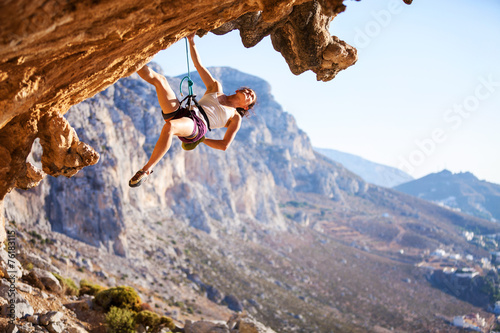 Young female rock climber on overhanging cliff