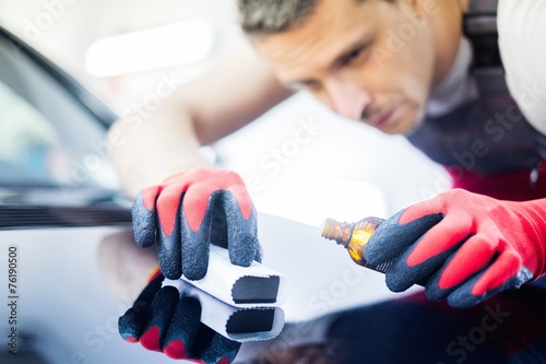 Worker on a car wash applying nano coating on a bonnet