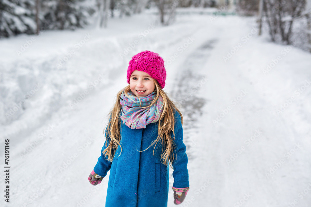 Portrait of a little girl dressed in a blue coat and a pink hat
