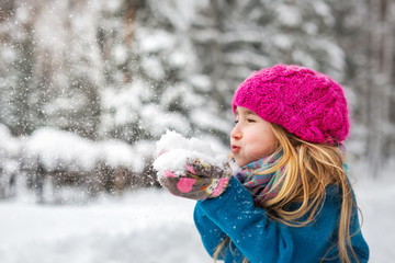 Cute little girl blows snow from hands