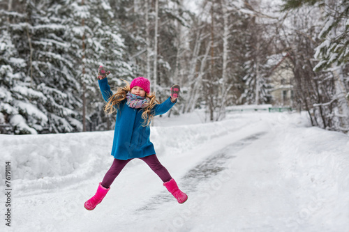 Little girl high jumps winter forest