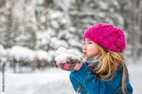 Cute little girl blows snow from hands
