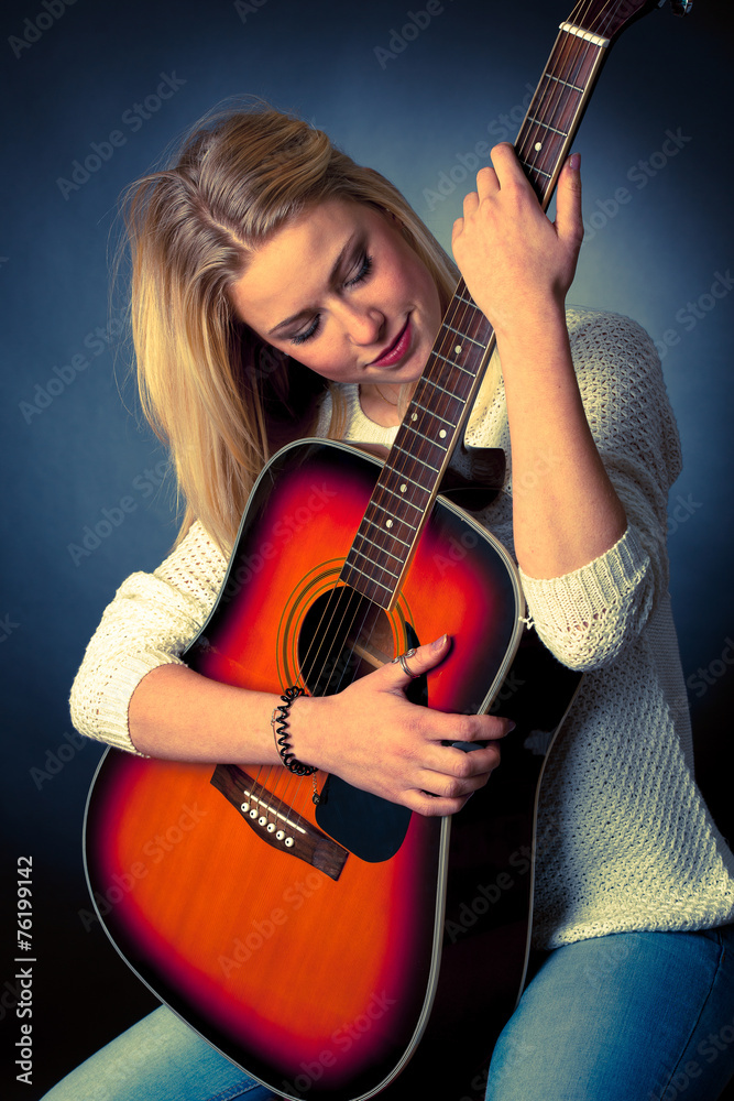 Portrait of young blonde guitar player woman