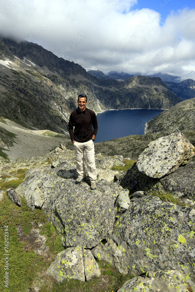 Un homme posant en haut de la montagne devant un lac