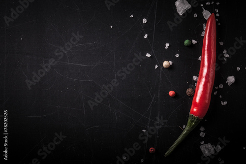 Red hot chilli pepper with sea salt and colored pepper on black