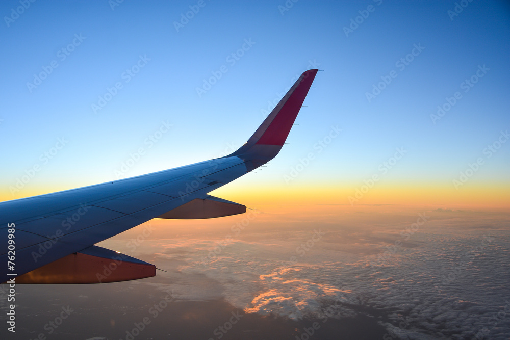 Fototapeta premium airplane flying over clouds with evening sky