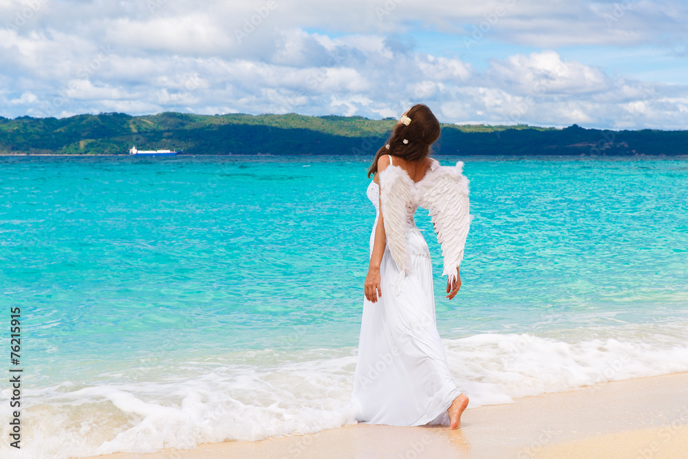 Beautiful young bride with angel wings on the sea coast. Tropica Beautiful young bride with angel wings on the sea coast. Tropica