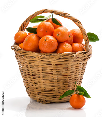 ripe tangerines with green leaves in basket