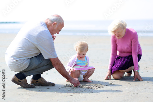 Grandparents with granddaughter playing n the beach