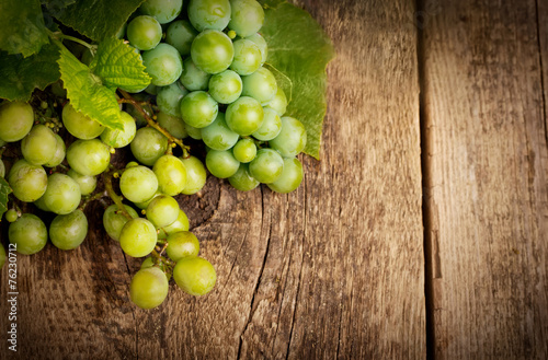 Grapes with leaves on the wood background close up
