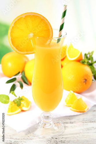 Glass of orange juice with straw and slices