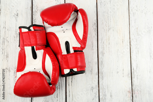 Pair of boxing gloves on color wooden background