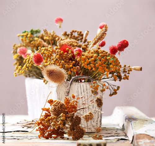Dried flowers in pot on bright background