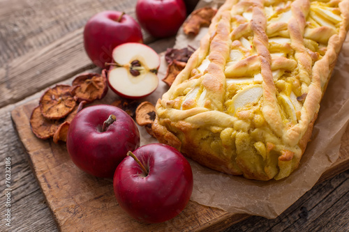 Apple pie on a board with fresh apples
